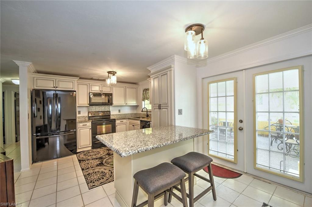 19066 Flamingo Road Fort Myers, FL 33967 - Photo 3 of 29 a kitchen with granite countertop a refrigerator and chairs