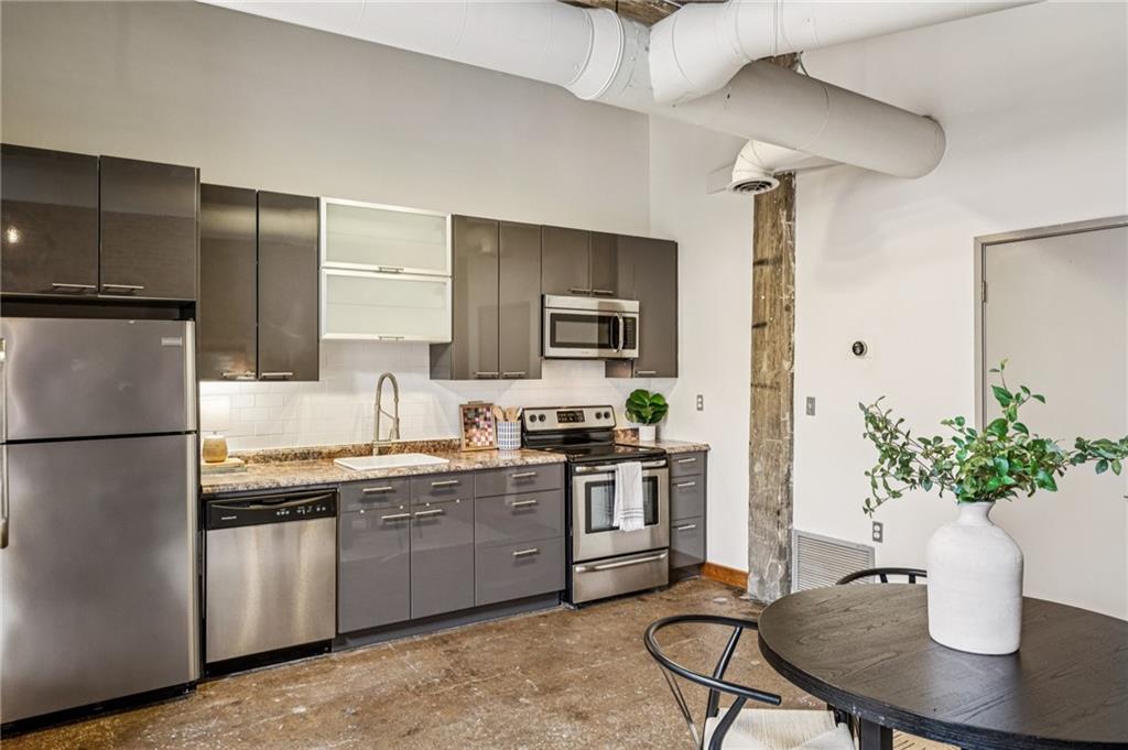 659 Auburn Avenue Northeast, Unit 229 Atlanta, GA 30312 - Photo 9 of 40 a kitchen with stainless steel appliances granite countertop a stove a sink dishwasher a refrigerator and a dining table with wooden floor
