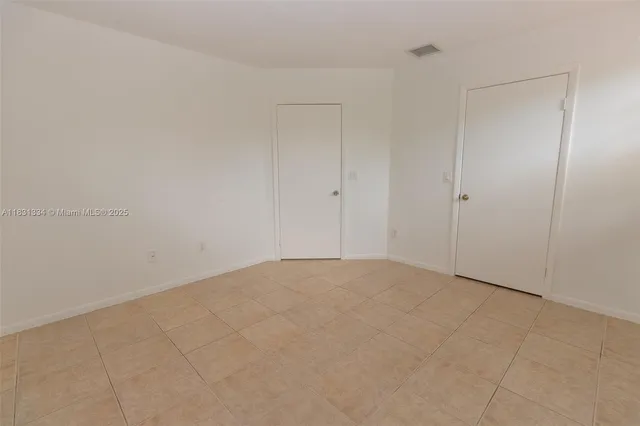 a view of an empty room and chandelier fan