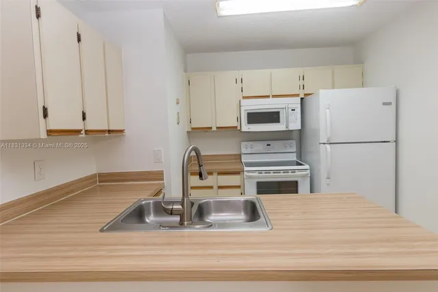 a kitchen with a refrigerator a stove a sink and white cabinets