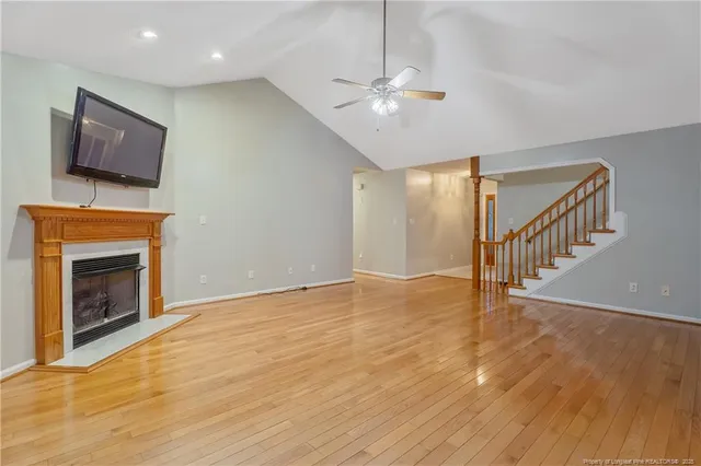 a view of an empty room with wooden floor and a fireplace