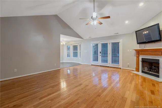 a view of an empty room with wooden floor fireplace and a window