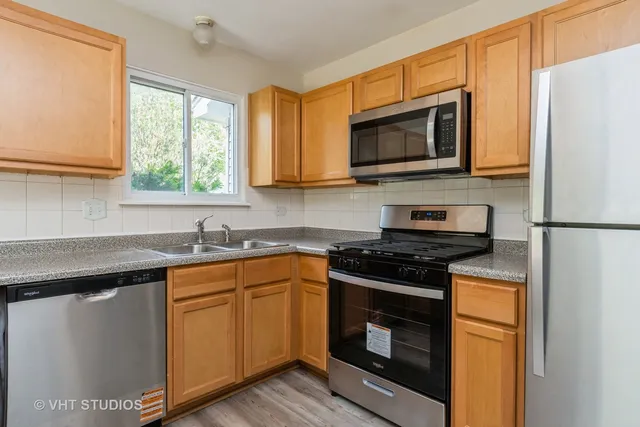 a kitchen with stainless steel appliances granite countertop a stove microwave refrigerator and sink