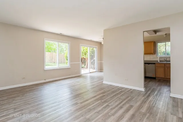 an empty room with wooden floor and a kitchen