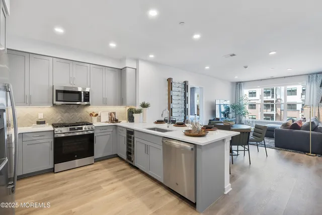 a kitchen with stainless steel appliances granite countertop a stove top oven a sink dishwasher a dining table and chairs with wooden floors