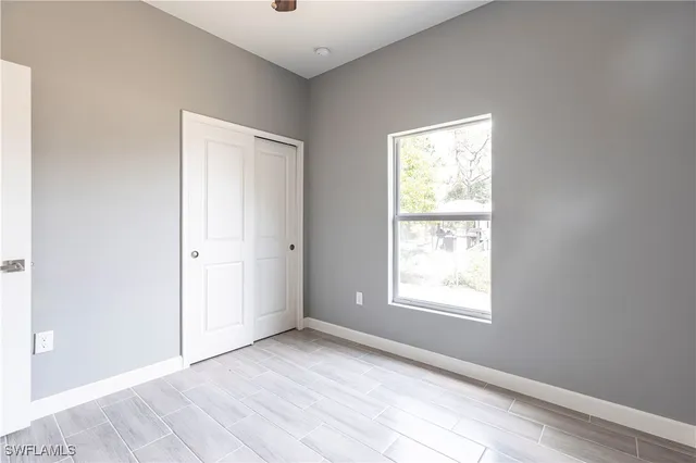 a view of an empty room with wooden floor and closet