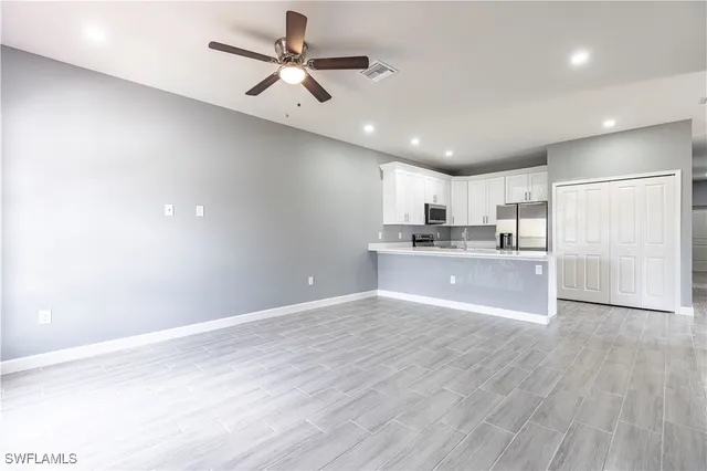 an empty room with wooden floor ceiling fan and windows