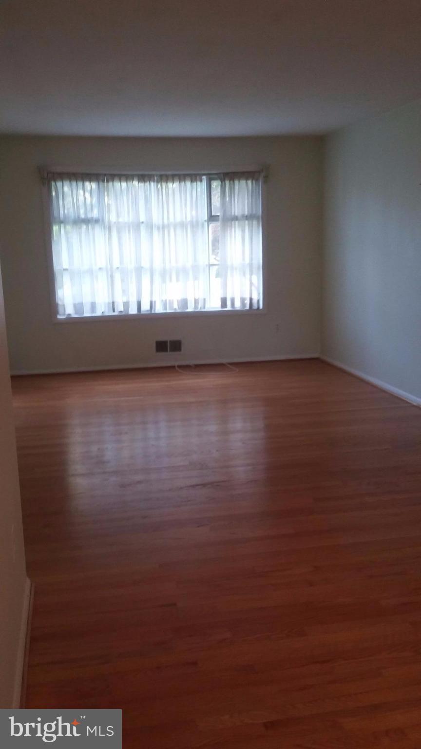 8804 Crandall Road Lanham, MD 20706 - Photo 8 of 11 an empty room with wooden floor and windows
