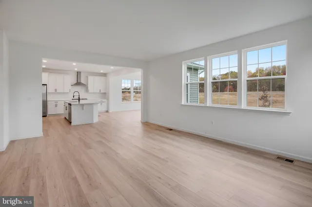 a view of an empty room and a kitchen