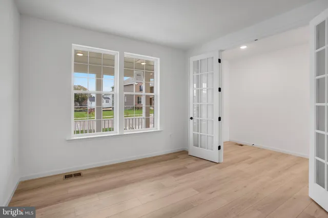 an empty room with wooden floor and windows