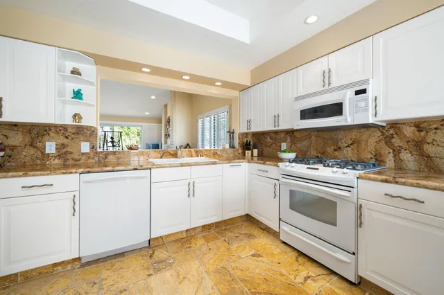 a view of living room with granite countertop kitchen island a sink a stove and a wooden floors