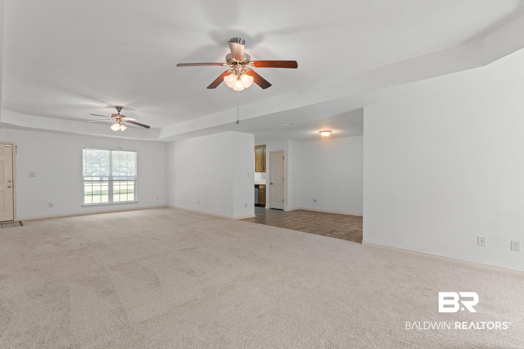 10535 Rhett McConnell Road Theodore, AL 36582 - Photo 12 of 36 Unfurnished living room featuring light colored carpet, ceiling fan, and a raised ceiling