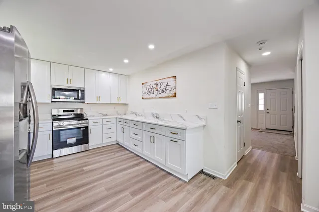 a kitchen with stainless steel appliances a refrigerator stove and white cabinets