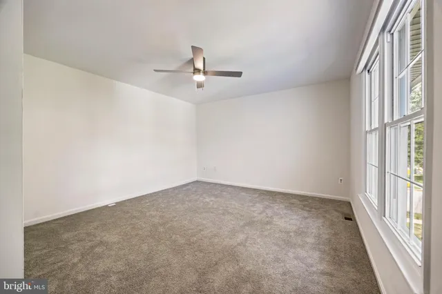 an empty room with windows and ceiling fan