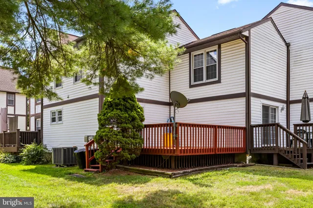 a view of a house with a yard deck and a large tree