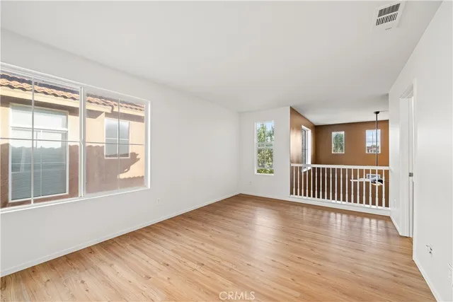an empty room with wooden floor ceiling fan and windows