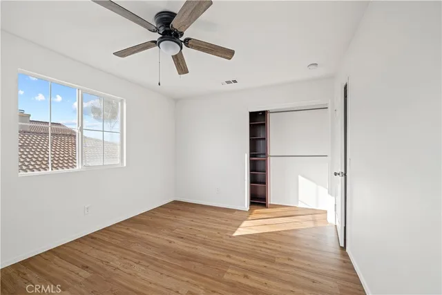 a view of empty room with wooden floor and fan