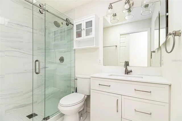 a bathroom with a granite countertop sink a toilet and shower
