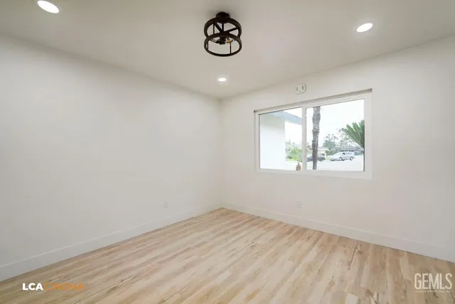 a view of an empty room with wooden floor and kitchen