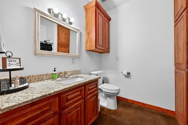 a bathroom with a granite countertop sink and a toilet