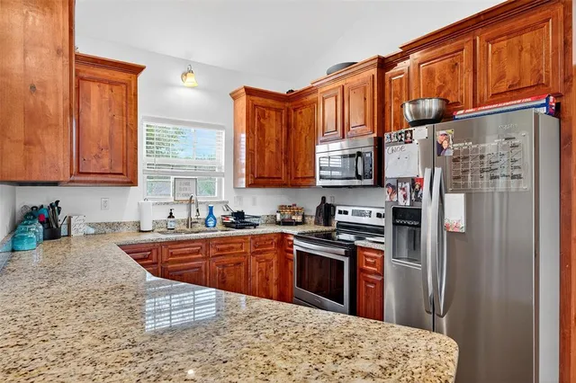 a kitchen with stainless steel appliances granite countertop a refrigerator a sink dishwasher a stove with wooden cabinets