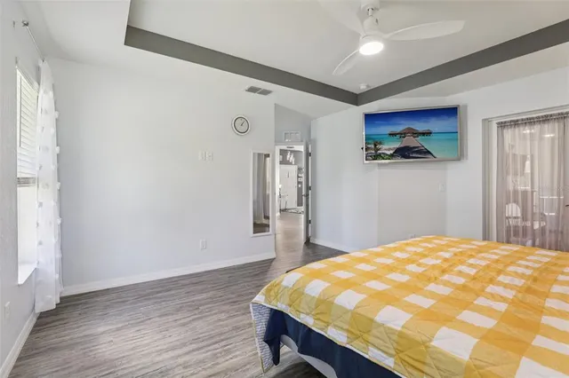 a bedroom with a bed and a dresser with wooden floor