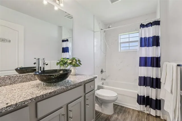 a bathroom with a granite countertop sink a toilet and shower