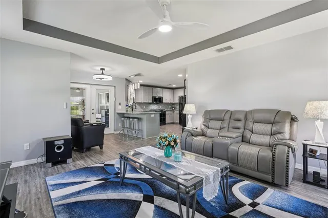 a living room with furniture kitchen view and a chandelier
