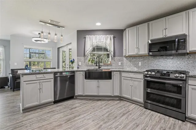 a kitchen with stainless steel appliances granite countertop a stove a sink and a microwave