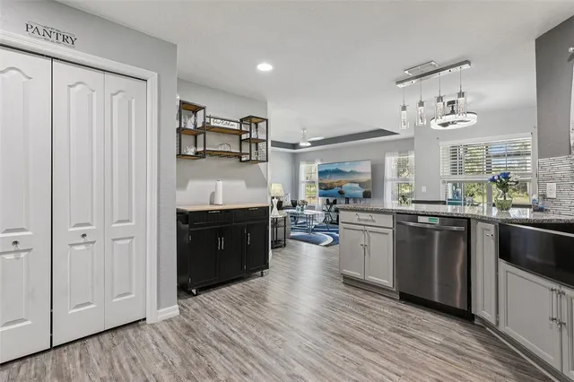 a kitchen with stainless steel appliances granite countertop a refrigerator a sink dishwasher a stove and white countertops with wooden floor