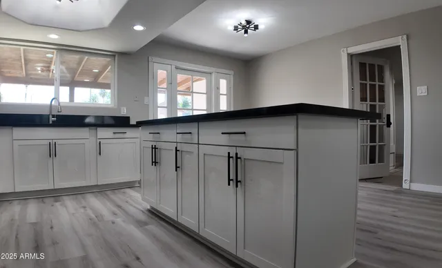 a kitchen with stainless steel appliances granite countertop a refrigerator a sink dishwasher a stove and white countertops with wooden floor