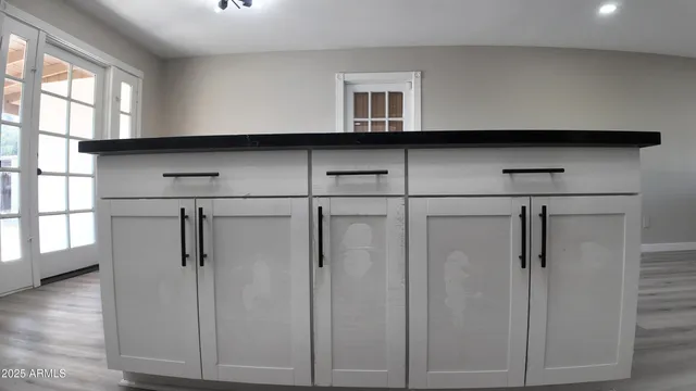 a kitchen with stainless steel appliances granite countertop a refrigerator a sink dishwasher a stove and white countertops with wooden floor