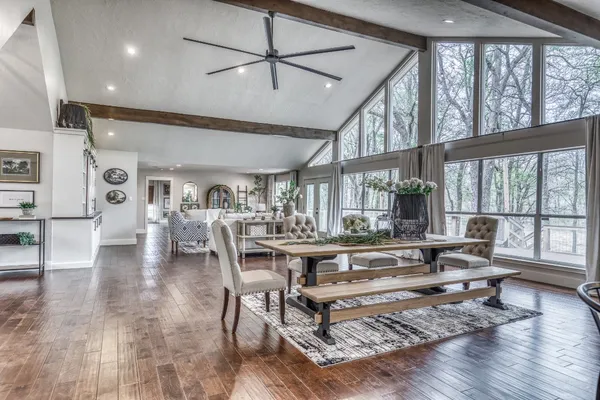 a living room with lots of furniture wooden floor and a large window
