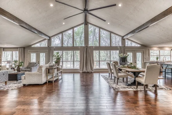 a dining room with wooden floor white walls and windows