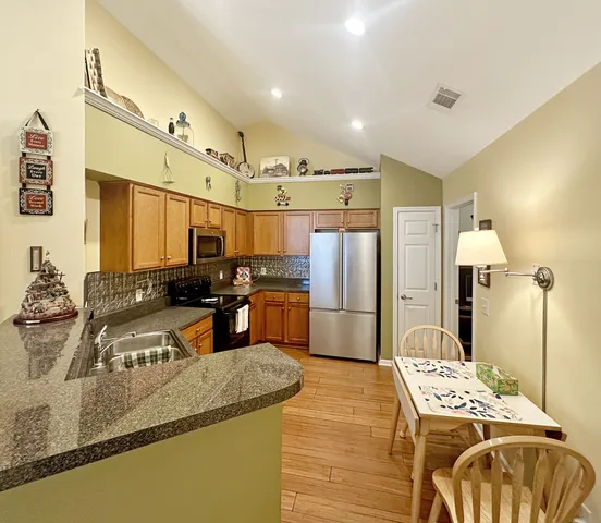 a kitchen with stainless steel appliances granite countertop a sink a stove and a refrigerator