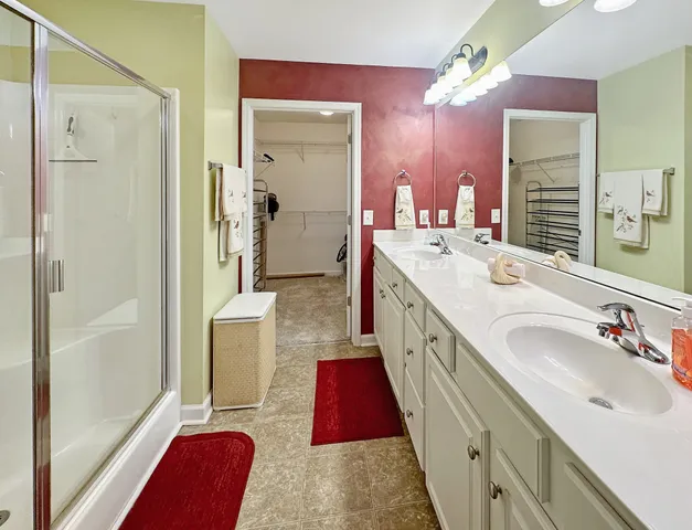 a spacious bathroom with a double vanity sink a mirror a bathtub and a shower