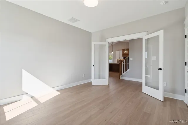 a view of an empty room with wooden floor and a window