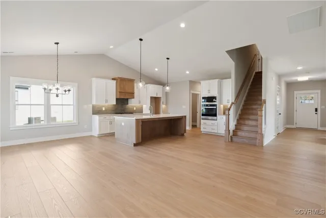 a large kitchen with cabinets wooden floor and a chandelier