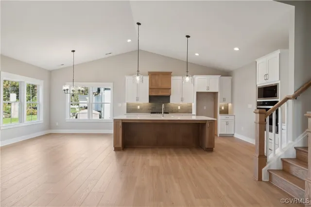 a large kitchen with a center island wooden floor stainless steel appliances and windows