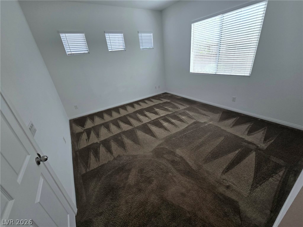 4748 Ritual Street North Las Vegas, NV 89031 - Photo 11 of 31 Well-lit room with distinctive patterned carpeting and ample natural light through multiple windows.