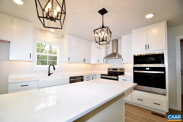 a kitchen with stainless steel appliances a sink a stove a refrigerator and white cabinets