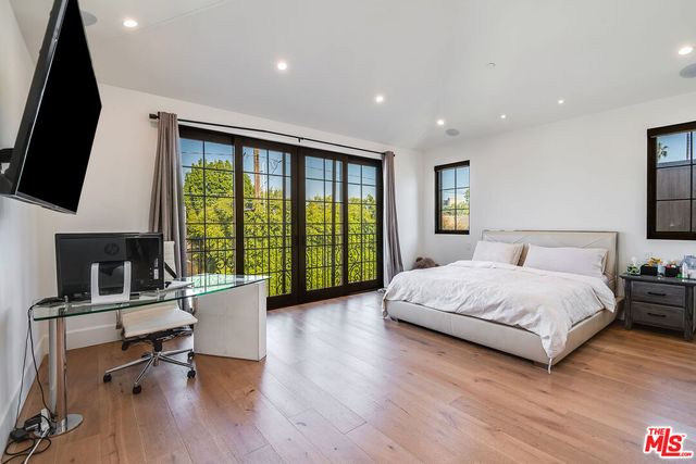 a spacious bedroom with a large bed and a flat tv screen