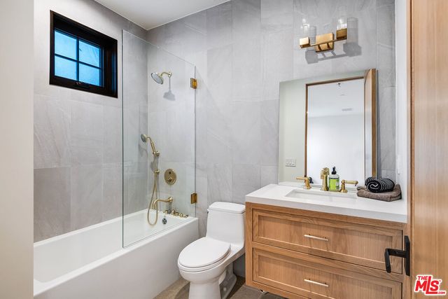 a bathroom with a bathtub shower sink vanity and toilet