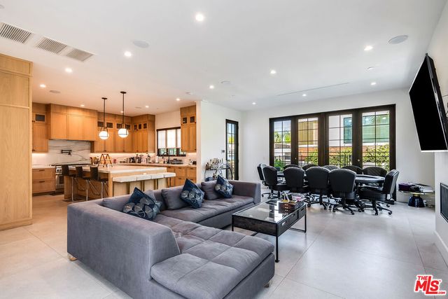 a living room with furniture kitchen area and a large window