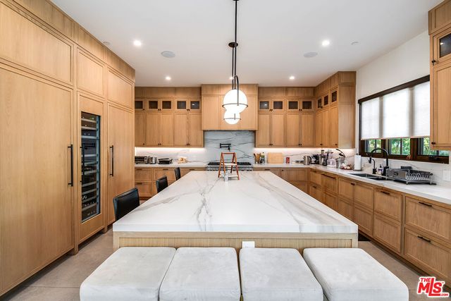 a large kitchen with kitchen island a large counter top space a sink stainless steel appliances and windows