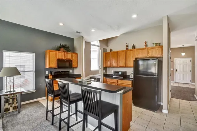 a kitchen with stainless steel appliances granite countertop a stove a refrigerator a sink a dining table and chairs with wooden floor