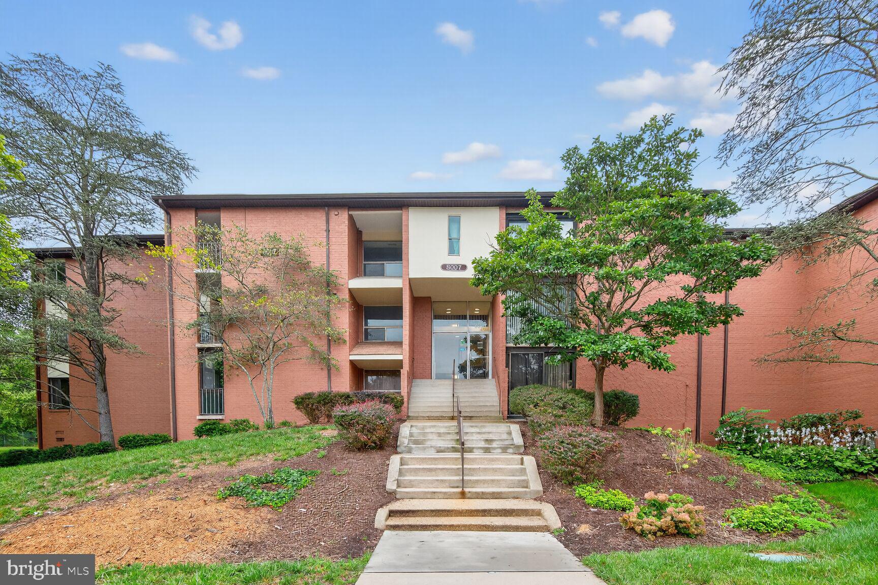 8007 Mandan Road, Unit 203 Greenbelt, MD 20770 - Photo 23 of 25 a front view of a house with a yard and potted plants