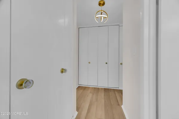 a view of a hallway with wooden floor and closet