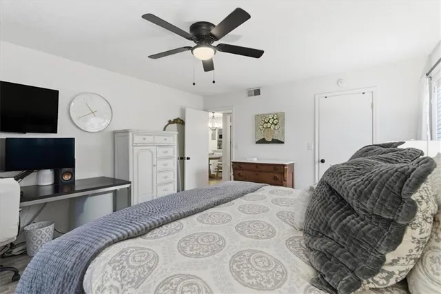 a bedroom with a bed a dresser and a chandelier