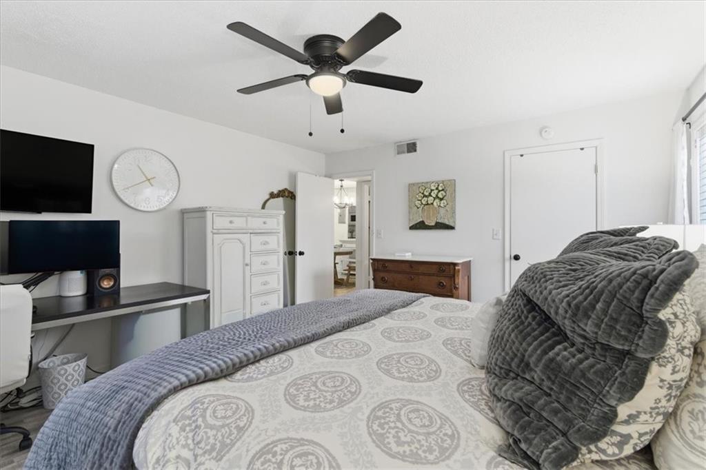 6851 Roswell Road, Unit J14 Sandy Springs, GA 30328 - Photo 12 of 41 a bedroom with a bed a dresser and a chandelier